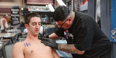 Tattoo artist working on a man's chest tattoo.