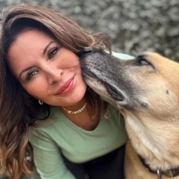 Woman receiving a dog’s affectionate lick on the cheek.