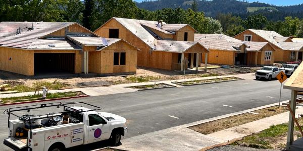 New houses under construction in a developing neighborhood with a work truck nearby.