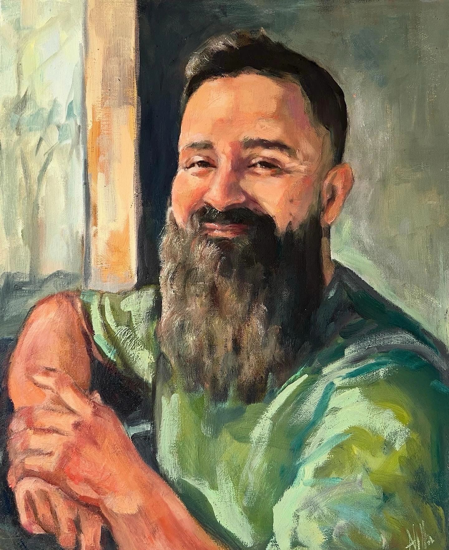 Portrait of a smiling man with a beard in a green shirt.