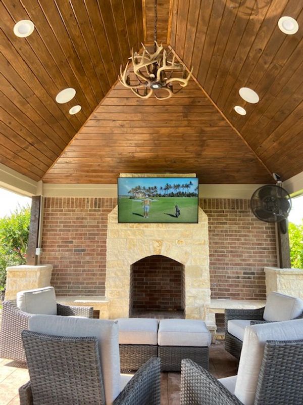 Cozy outdoor seating area with TV and antler chandelier.