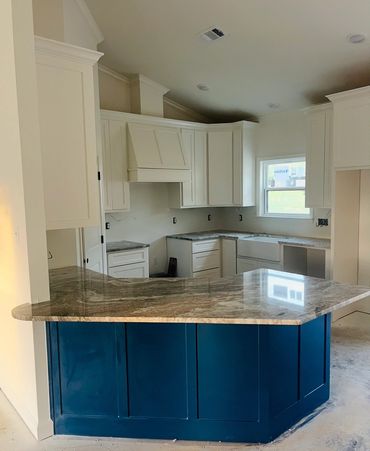 Modern kitchen with white cabinets and a blue island with granite countertop.