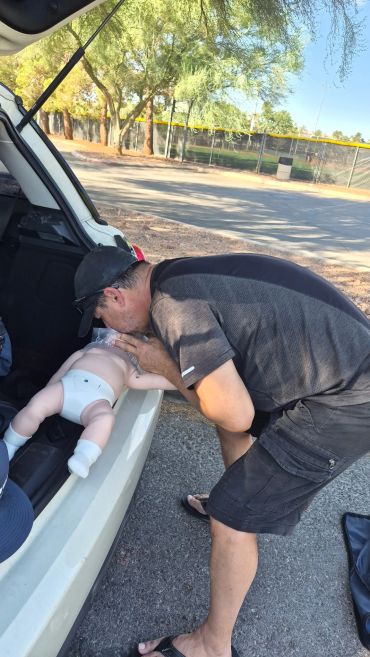 Man kissing a baby doll on car trunk.