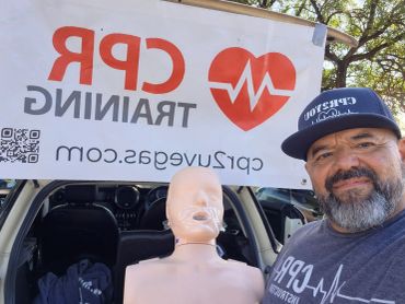 Man posing with CPR training mannequin and banner.