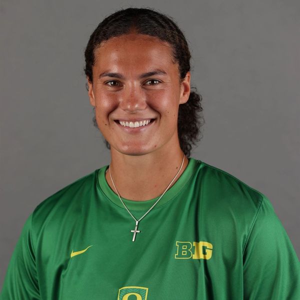 Smiling athlete in green sportswear with a cross necklace.
