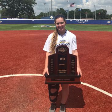 Young athlete proudly holding a championship trophy on a baseball field.