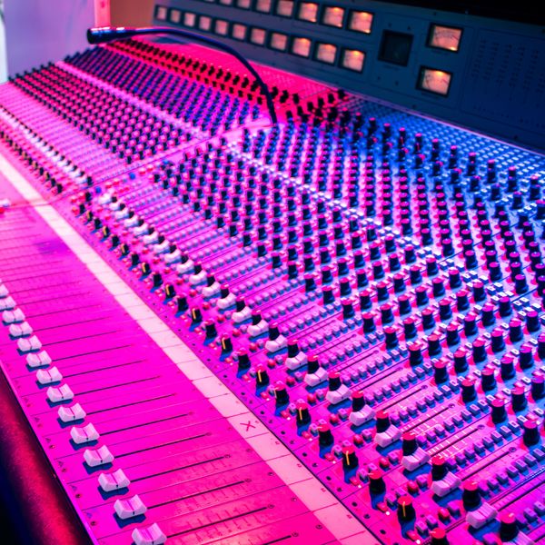 Close-up of a colorful audio mixing console with knobs and sliders.