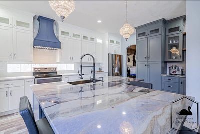 Modern kitchen with a large marble island and blue cabinetry.