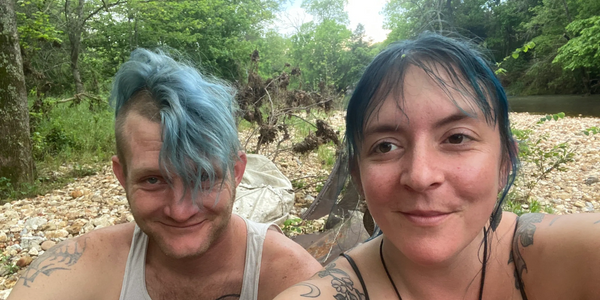 A photo of the owners of Seven Mornings Farm sitting on a riverbank. 