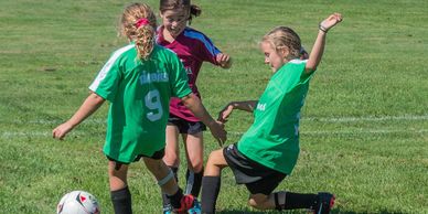 Three young girls playing soccer