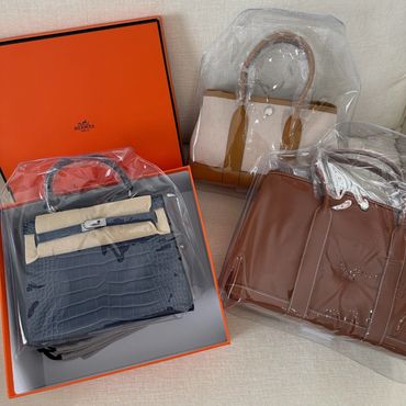 Three luxury handbags, one in an orange box.