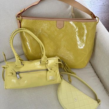 Three stylish yellow handbags on a beige sofa.