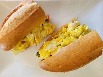 Two sandwiches filled with scrambled eggs on a white plate.