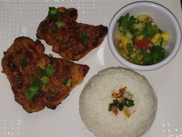 Grilled chicken with steamed rice and fresh mango salsa on a white plate.