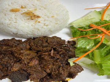 Plate with white rice, seasoned beef, and fresh salad with lettuce, cucumber, and carrots.