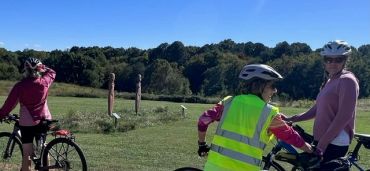 Three cyclists prepare to ride in a scenic outdoor area.