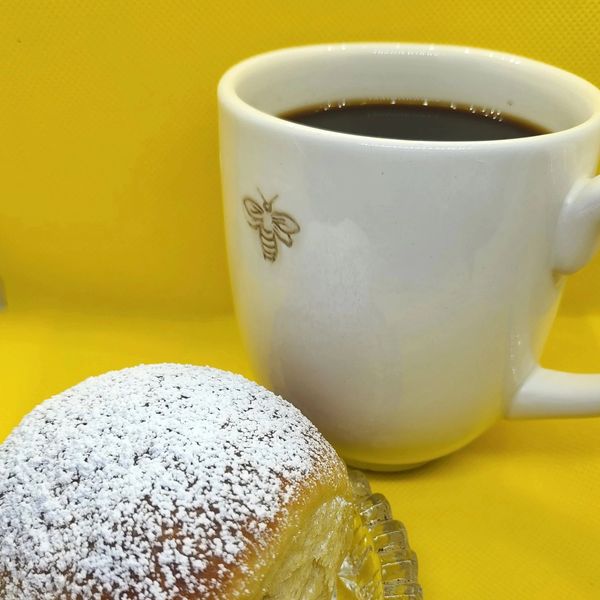 a picture of a deliciously looking sugar sprinkled bun served wit a cup morning coffee