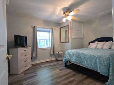 Cozy bedroom with a bed, dresser, TV, and window.