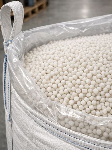 Large sack filled with small white pellets, lined with plastic.
