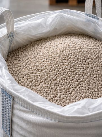 Large white sack filled with beige granules, likely industrial material or pellets.