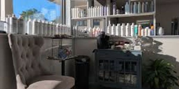 Cozy salon corner with tufted chair and shelves of beauty products.