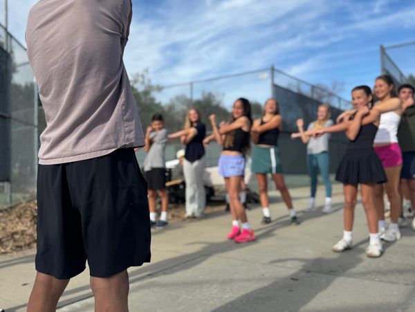 Group of young people stretching outdoors on a sunny day.