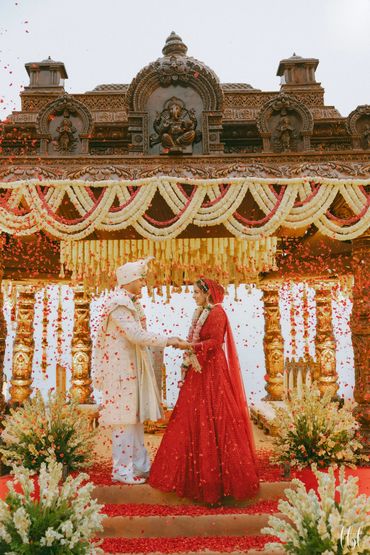 Sacred varmala moment, South Indian temple–style mandap and floral shower, a Goan-sundowner