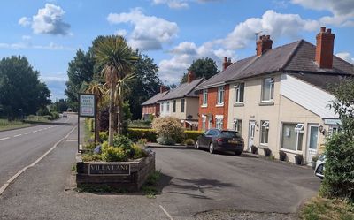 Quiet suburban street with houses and a car under a blue sky.