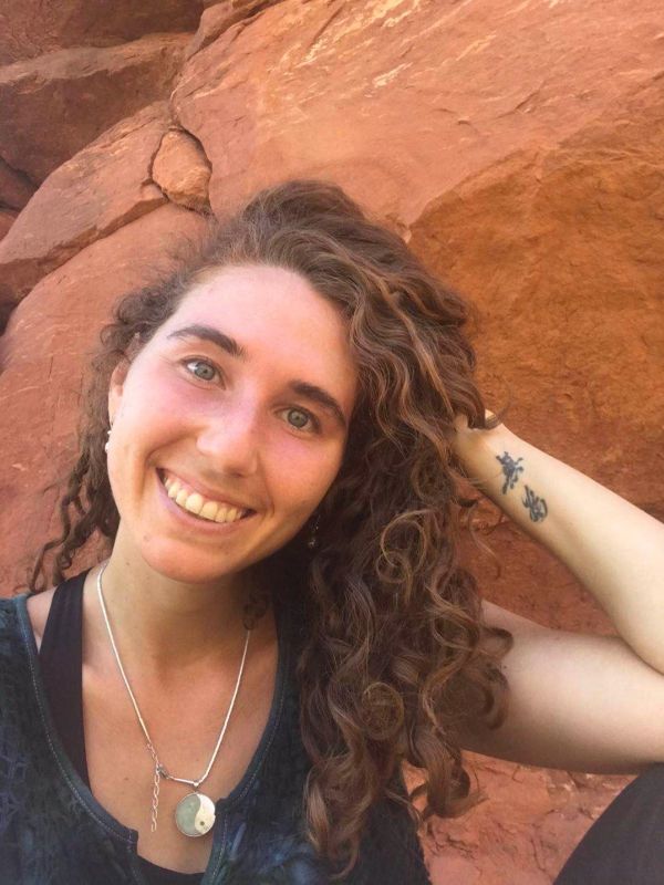 Smiling woman with curly hair in front of red rocks.