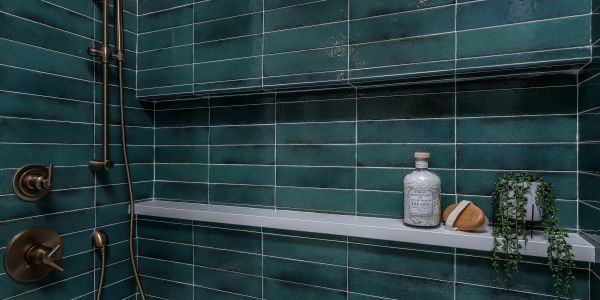 Modern shower with teal tiles and minimalist shelves.