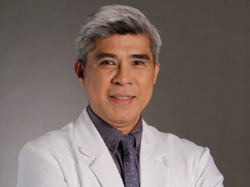 Confident middle-aged male doctor in white coat with arms crossed.