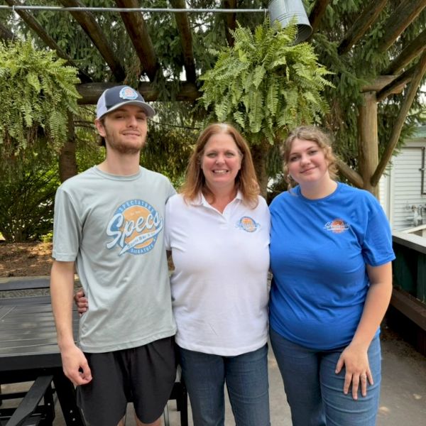 Three people posing outdoors with smiles.