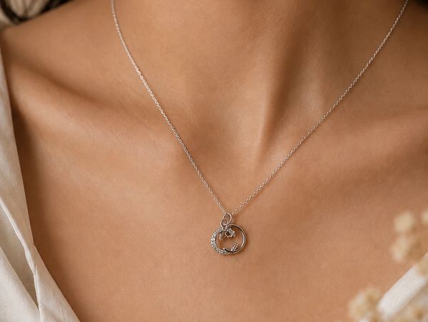Silver necklace with circular pendant on woman's neck.