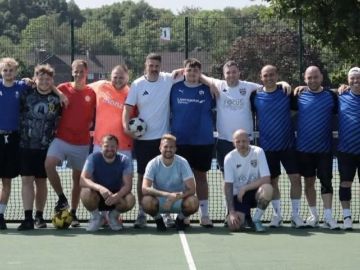 Group of men posing on a sports court with a soccer ball.
