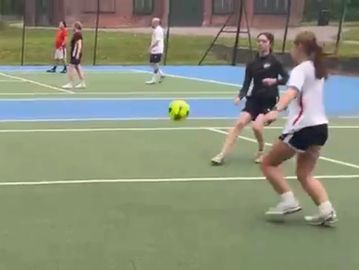 Four people playing soccer on an outdoor court.