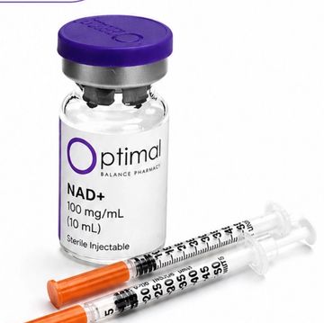Vial of NAD+ solution with two syringes on a white surface.