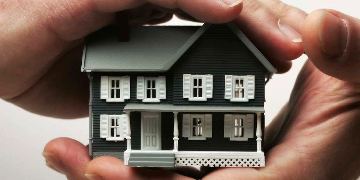 Hands holding a miniature replica of a house.