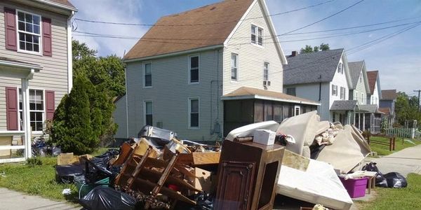 Photo of a pile of junk in someone's front yard.