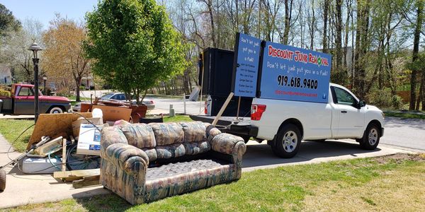 Picture of junk piled up on driveway with Discount Junk Removals truck next to it.