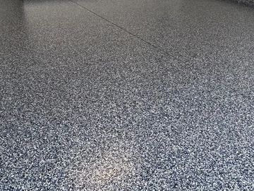 Clean, organized garage with speckled epoxy floor and neatly arranged tools.