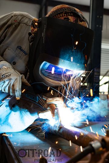 Person welding metal with protective gear and sparks flying.