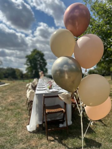 Pastel balloons near an outdoor dining table setup.