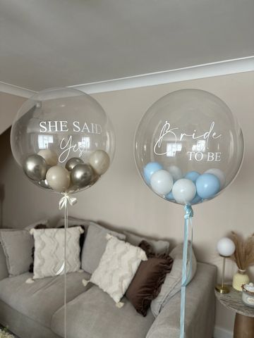 Two clear balloons with wedding-related text and colored balloons inside.