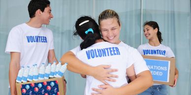 Volunteers warmly hugging while distributing supplies.
