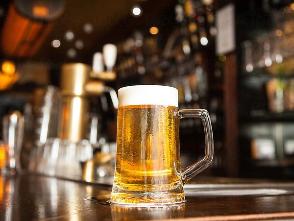 A cold beer on a wooden bar.