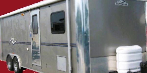 A silver travel trailer with two wheels and a side door, set against a red background.