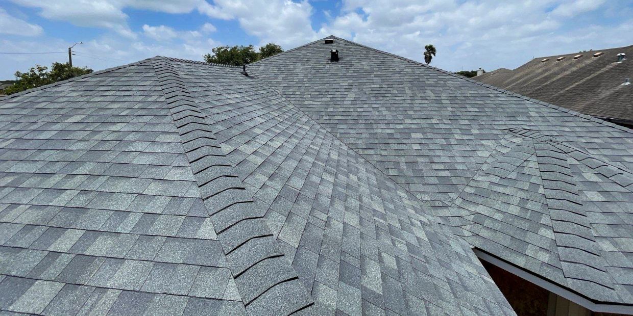 Gray asphalt shingle roof under a partly cloudy sky.