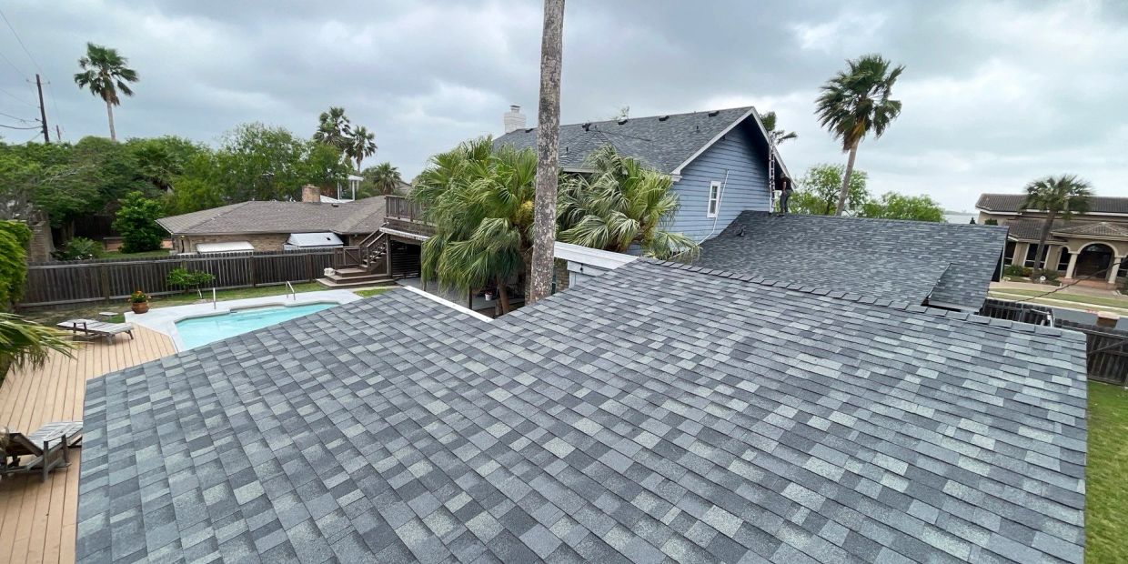 View of rooftops and backyard pool on a cloudy day.