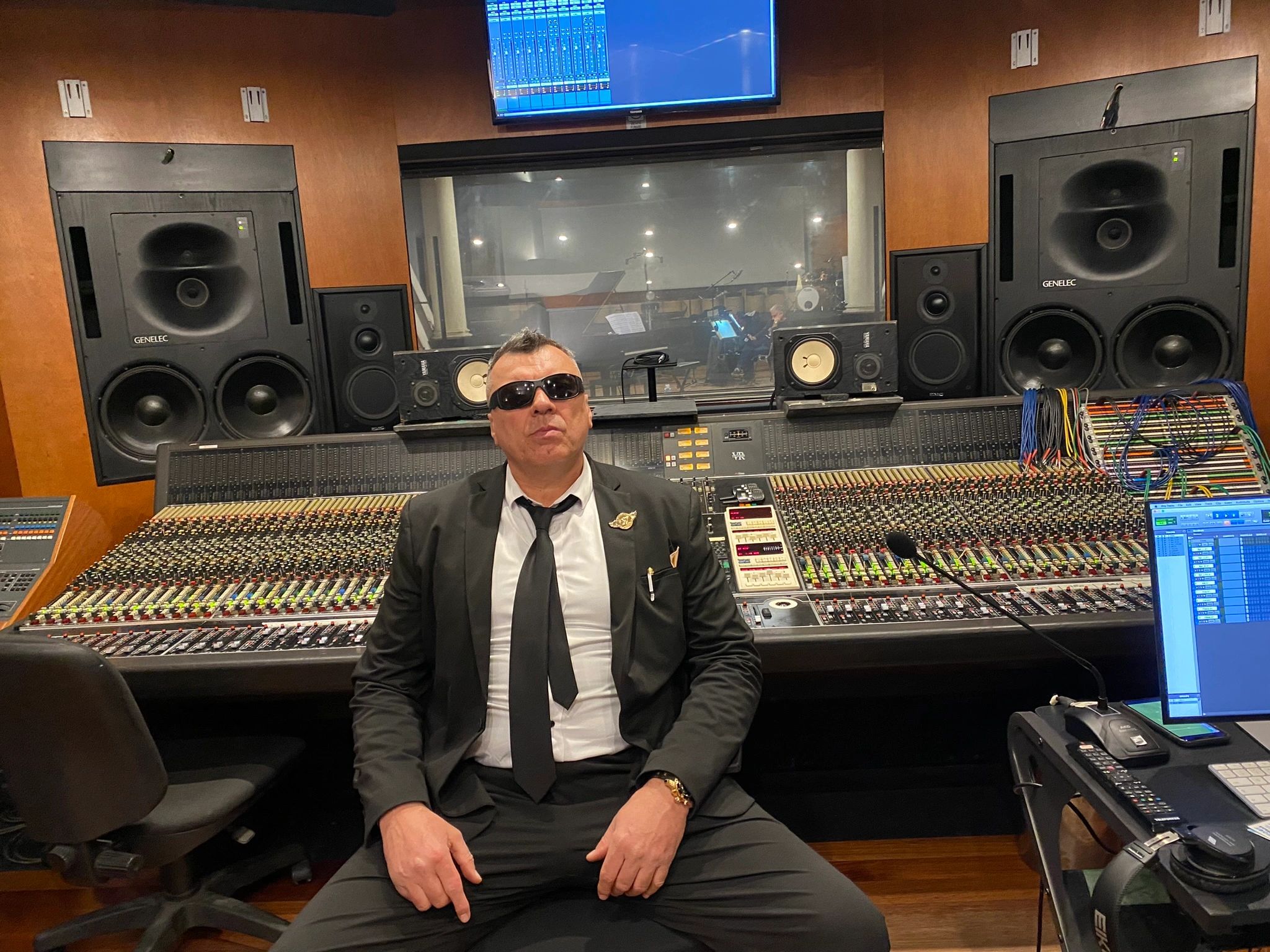 Man in sunglasses sitting in a recording studio.