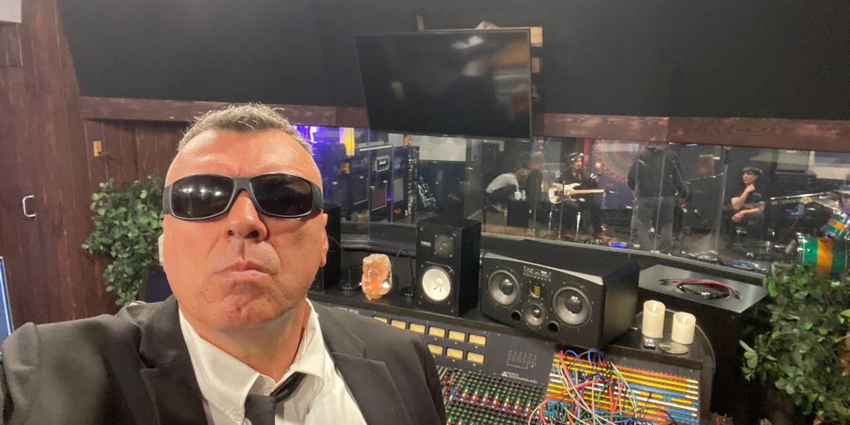 Man in sunglasses taking a selfie in a music studio.